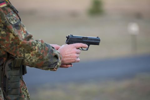 Ein Bundeswehrsoldat in Tarnfleck-Uniform hält mit beiden Händen eine Pistole