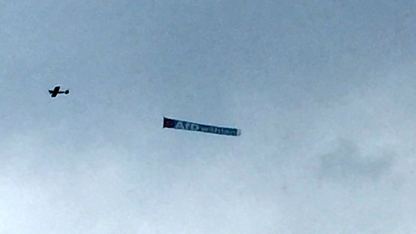 Ein Flugzeug zieht ein Banner mit "AfD wählen" über den Himmel von Schleswig-Holstein