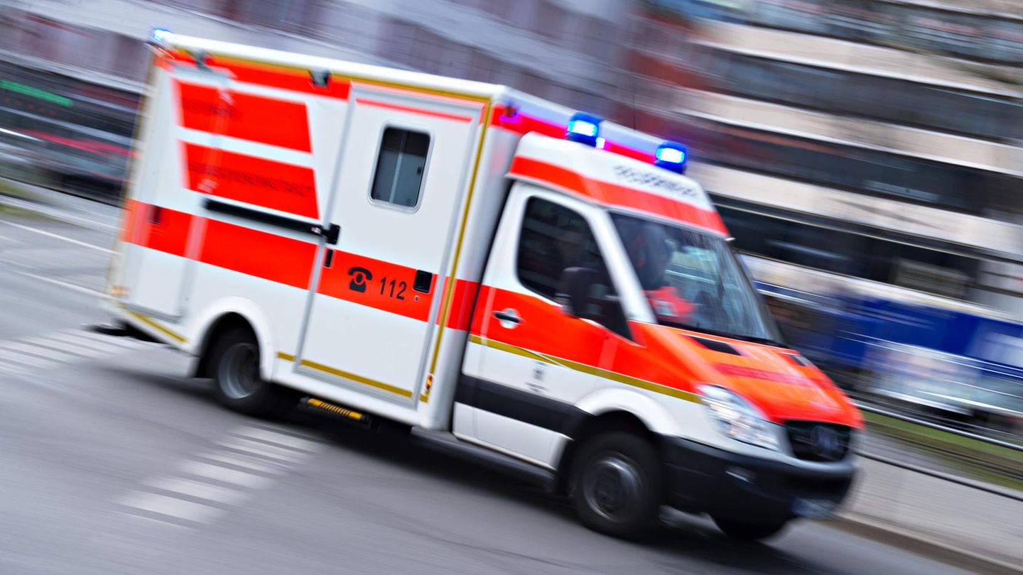 Ein Rettungswagen rast mit Blaulicht durch eine Straße in einer Großstadt