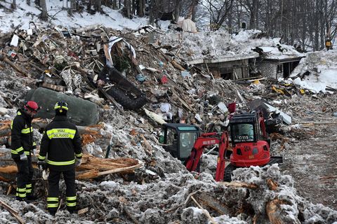 Zwei Feuerwehrmänner und ein Bagger stehen auf den Trümmern des von einer Lawine verschütteten Hotels Rigopiano in den Abruzzen
