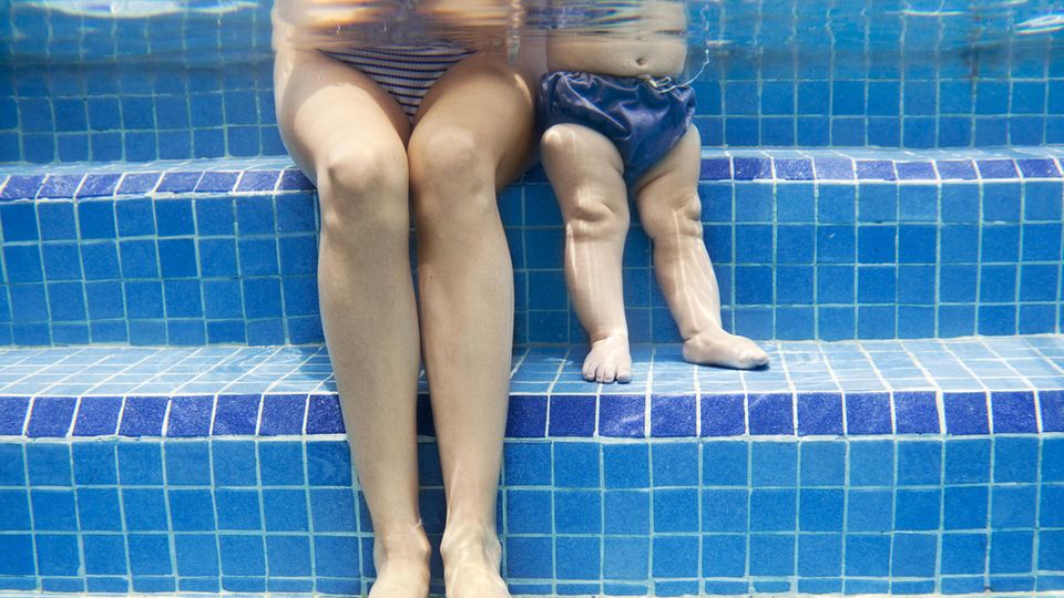 Eine Frau und ein Kleinkind sitzen in einem Schwimmbecken