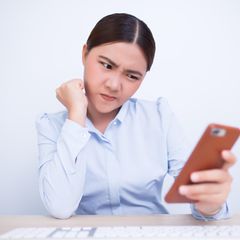 Eine Frau schaut skeptisch ihr iPhone an