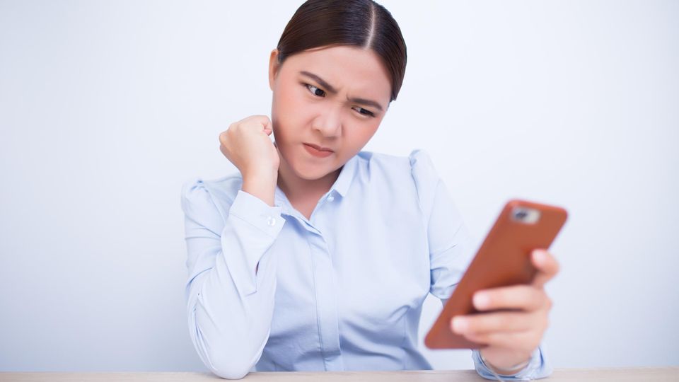 Eine Frau schaut skeptisch ihr iPhone an