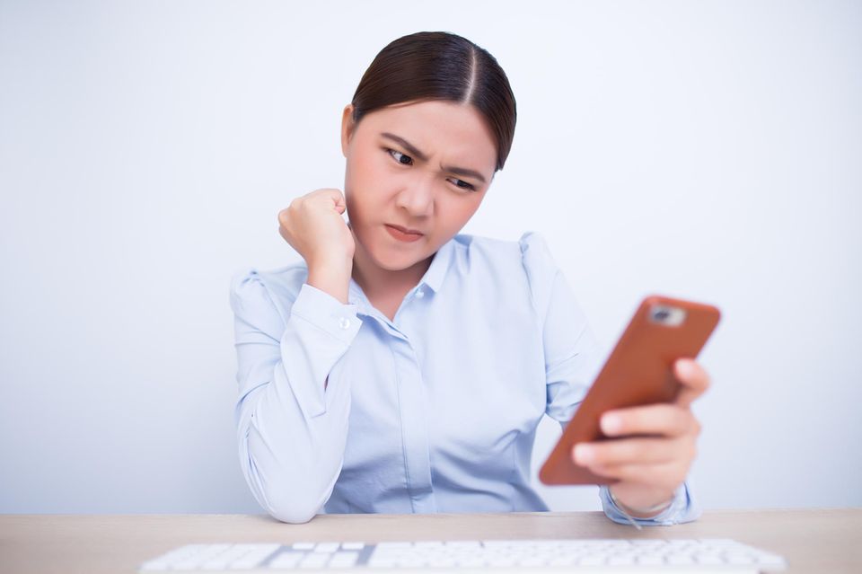 iPhone Trick Multitasking Apps abschießen Eine Frau schaut skeptisch ihr iPhone an