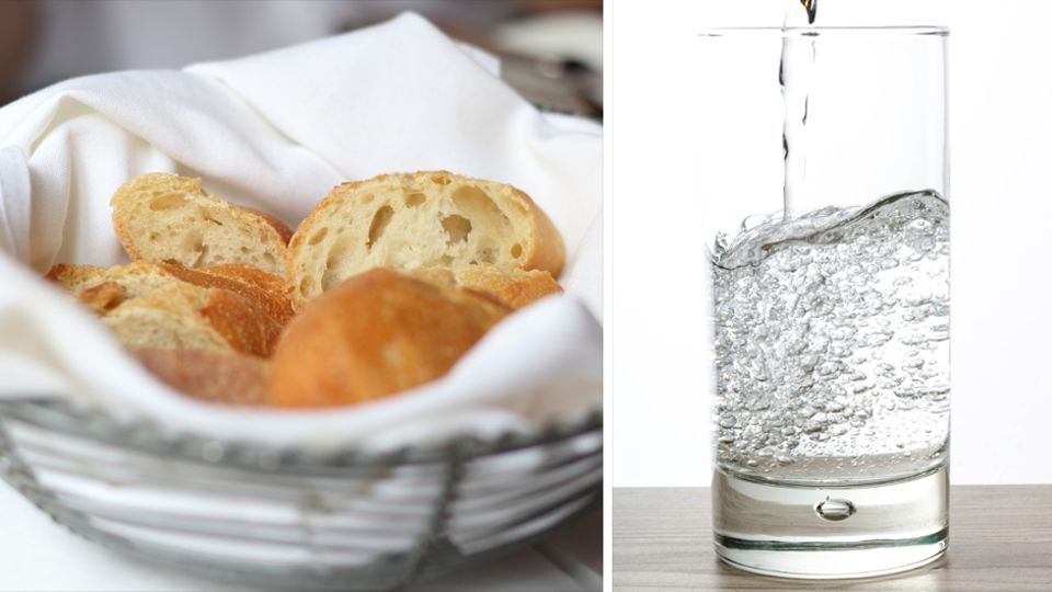 Ein Brotkorb und ein Glas Wasser stehen auf einem Tisch.