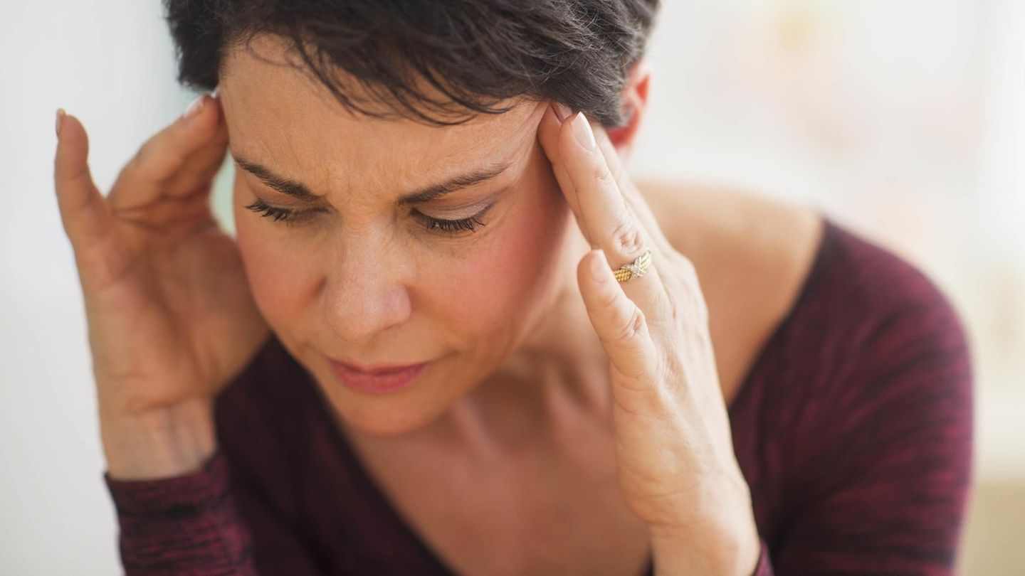 Eine Frau hat Kopfschmerzen und hält sich den Kopf.
