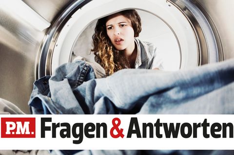 Eine Frau schaut entgeistert in ihre Waschmaschine