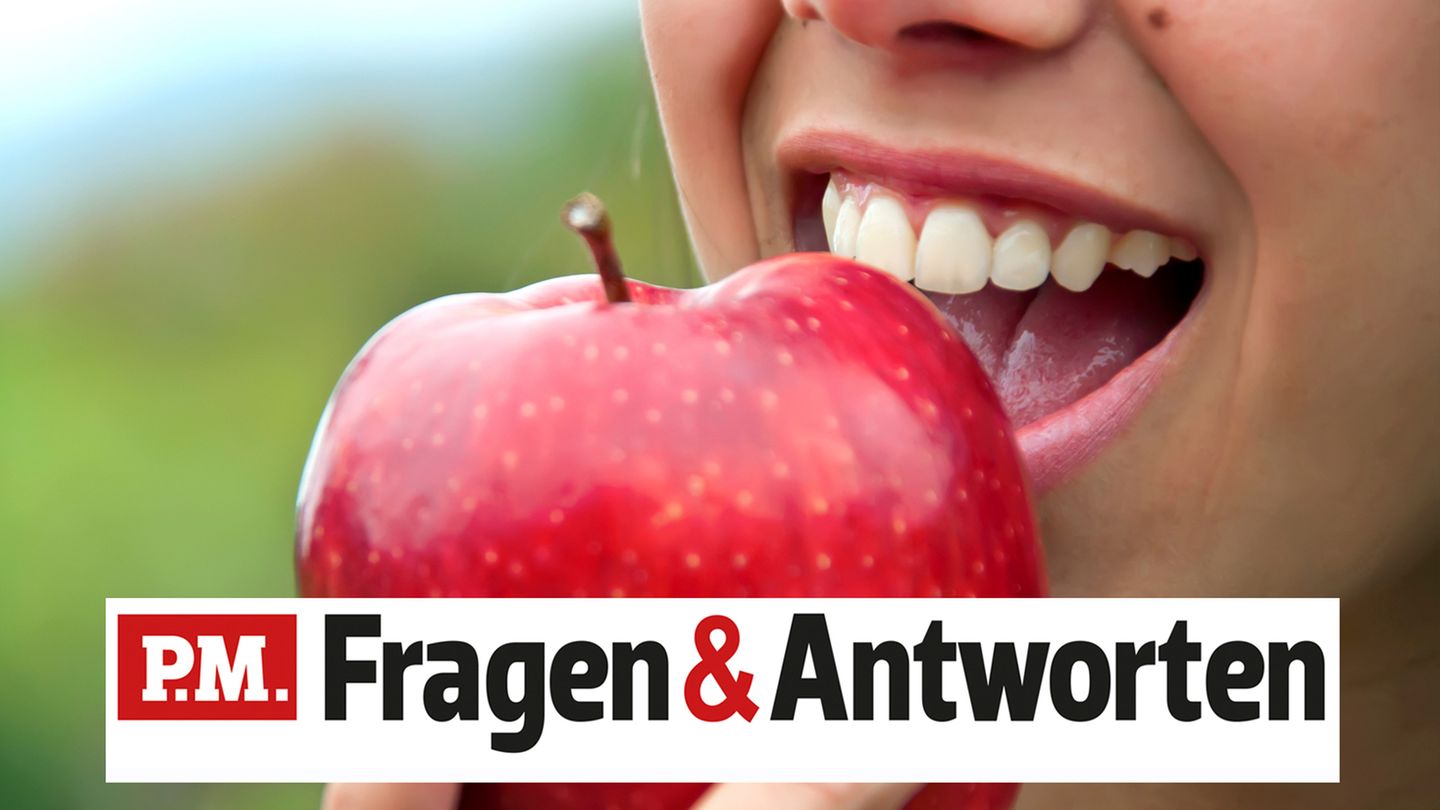 Eine Frau beißt lächelnd in einen Apfel