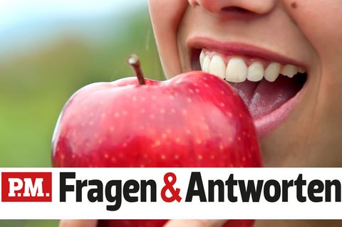 Eine Frau beißt lächelnd in einen Apfel