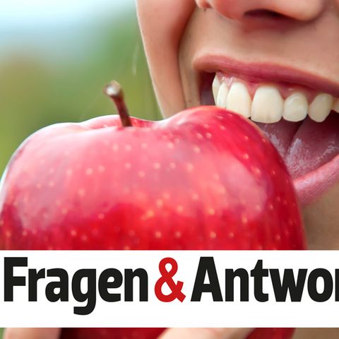 Eine Frau beißt lächelnd in einen Apfel
