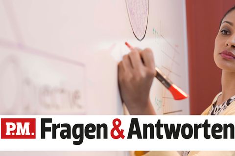 Eine Frau schreibt mit der linken Hand auf ein Flipchart