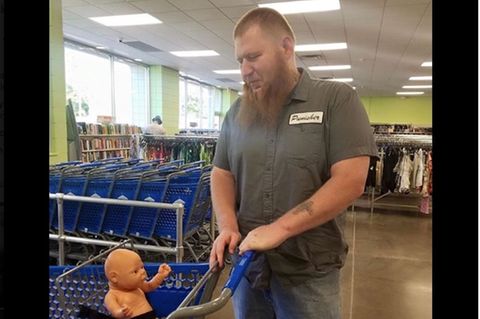 Vater geht mit Puppe im Einkaufswagen einkaufen