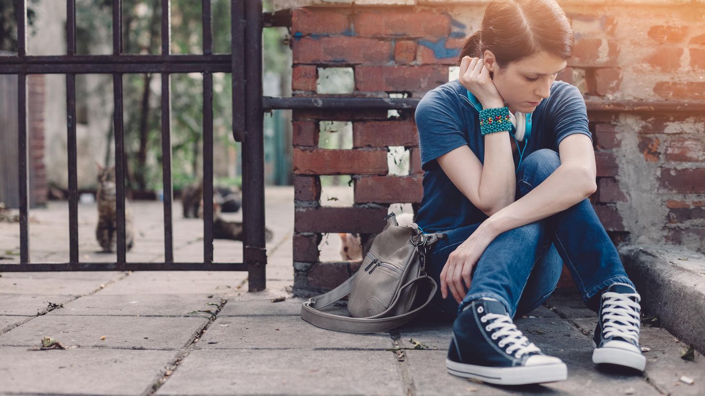 Ein weiblicher Teenager sitzt allein auf dem Bürgersteig
