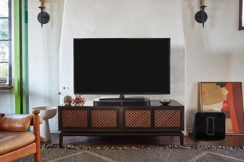 In einem schick eingerichteten Wohnzimmer steht ein Fernseher direkt auf der Sonos Playbar