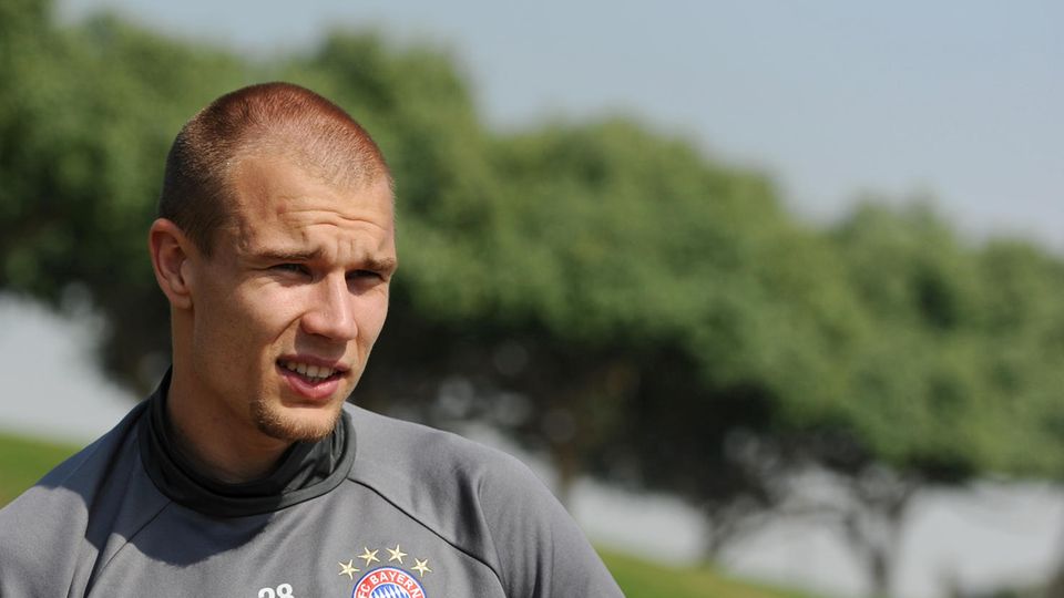 Holger Badstuber FC Bayern München Im grauen Trainingspullover des FC Bayern München steht Holger Badstuber auf dem Platz und blinzelt in die Sonne.