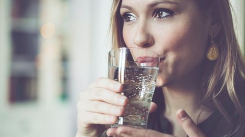 Frau trinkt Wasser mit Kohlensäure