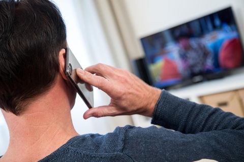Ein Mann telefoniert in seinem Wohnzimmer. Forscher prüfen seit zwanzig Jahren, ob Handystrahlen Krebs verursachen können.
