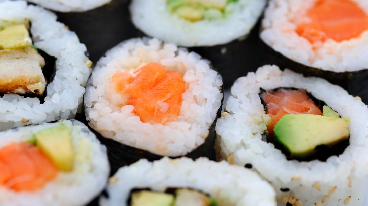 Sushi mit rohem Fisch liegt auf einem Teller.