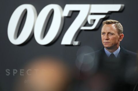 Schauspieler Daniel Craig steht im Anzug vor einer Wand mit großem 007-Logo. Er spielte in vier Filmen James Bond