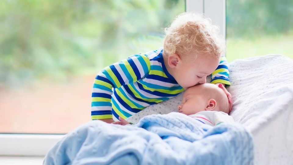 Großer Bruder küsst kleine Schwester auf Stirn Großer Bruder küsst kleine Schwester auf Stirn