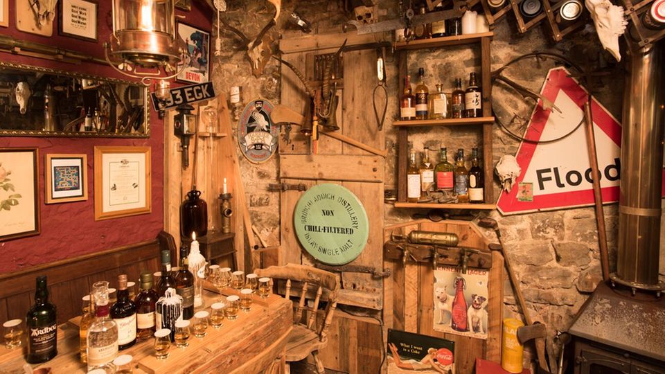 Dieses Gartenhäuschen sieht im Inneren aus wie ein Pub Das Innere des Pub-Gartenhäuschens mit vielen Flaschen und Dekoration an den Wänden
