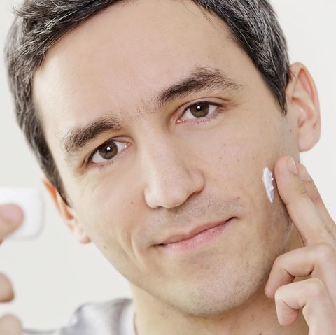 Ein Mann cremt sich das Gesicht ein.