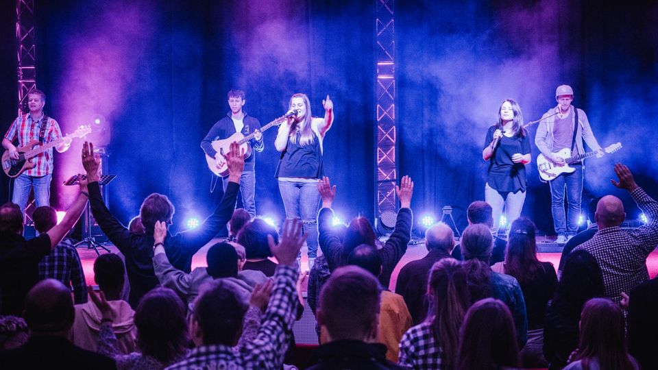 Freikirche: Die Band der Gemeinde spielt während des Gottesdienstes. Die Gläubigen singen mit, die Augen geschlossen, die Arme erhoben. Einigen laufen Tränen über die Wangen. Die Band der Gemeinde spielt während des Gottesdienstes. Die Gläubigen singen mit, die Augen geschlossen, die Arme erhoben. Einigen laufen Tränen über die Wangen.