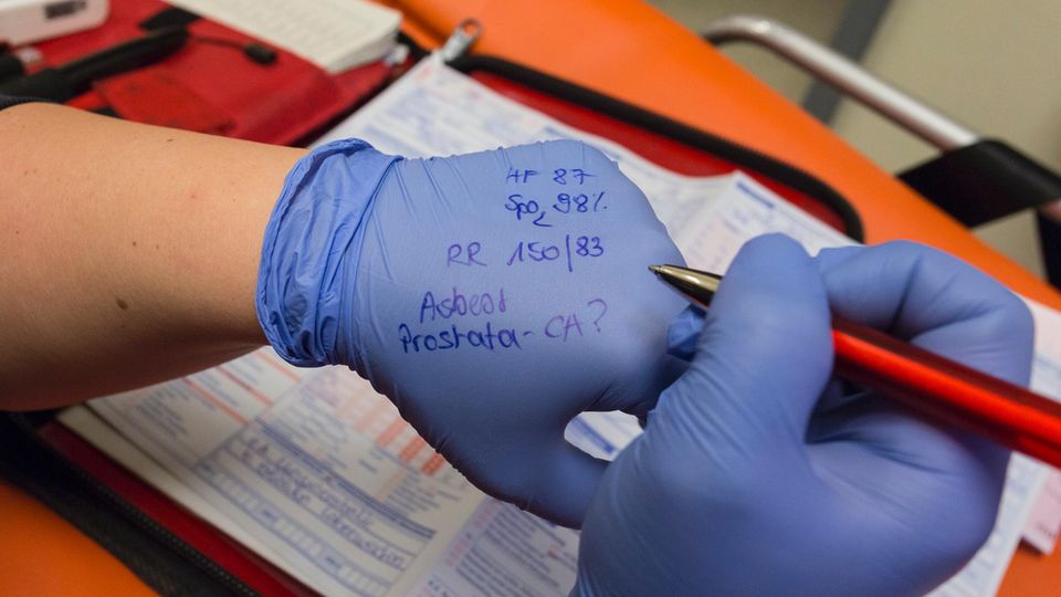 Rettungsassistentin Diana Weden notiert sich Messwerte und Vorerkrankungen ihres Patienten auf dem Handschuh.
