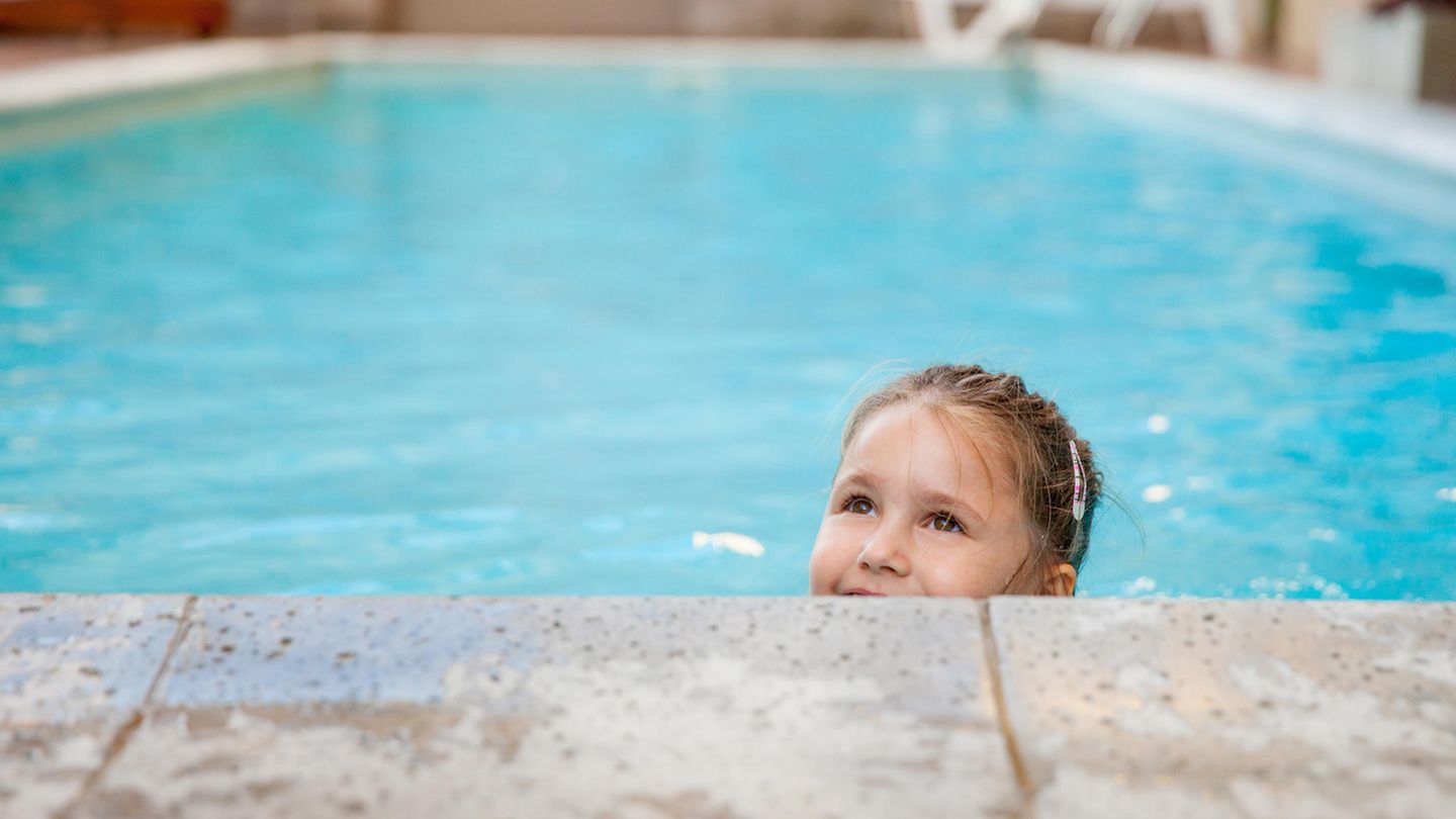 Ein kleines Mädchen schwimmt in einem Schwimmbecken.