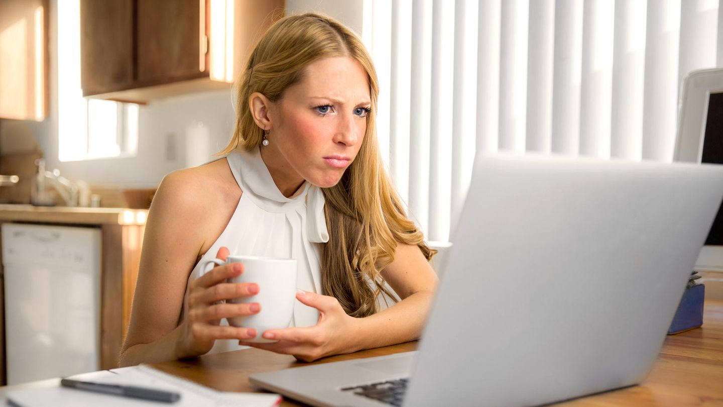 Eine blonde Frau schaut irritiert den Bilschirm ihres Laptops an