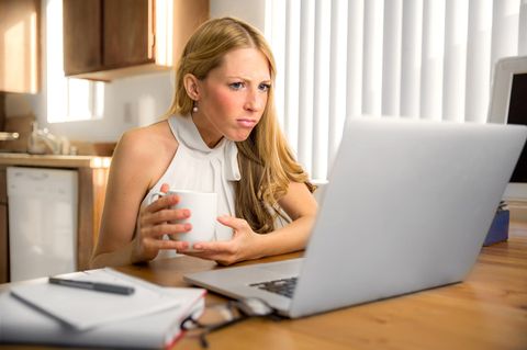 Eine blonde Frau schaut irritiert den Bilschirm ihres Laptops an