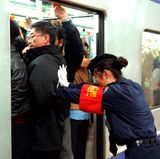 Peking in China    Feste drücken und zurückbleiben, bitte! Eine Mitarbeiterin der Metro von Peking schiebt die Fahrgäste in den gut gefüllten U-Bahn-Wagen.