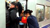 Peking in China    Feste drücken und zurückbleiben, bitte! Eine Mitarbeiterin der Metro von Peking schiebt die Fahrgäste in den gut gefüllten U-Bahn-Wagen.