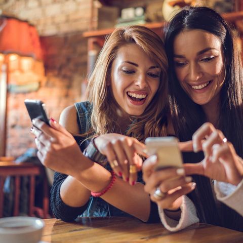 Zwei hübsche Frauen lesen Nachrichten auf dem Smartphone