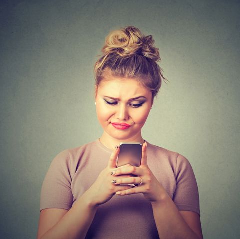 Eine Frau schaut genervt auf ihr Smartphone