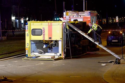 Ein Polizist klettert am 27. März.2017 in Berlin am Frankfurter Tor über eine Leiter auf einen umgestürzten Krankenwagen. Sieben Personen wurden bei dem Unfall verletzt.