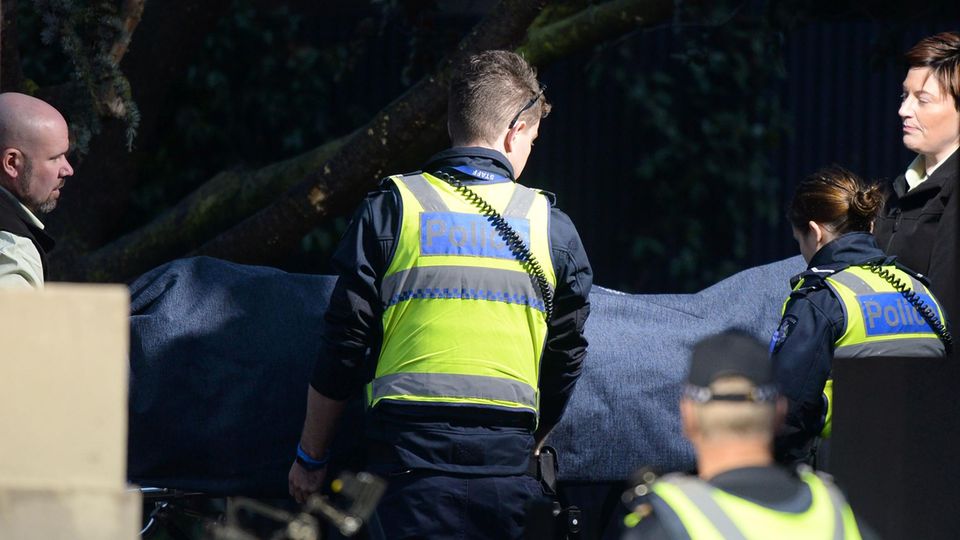 Geiselnahme Terror Australien Unter einem dunkelblauen Tuch verdeckt tragen zwei Männer und zwei Frauen eine Leiche vom Ort einer Geiselnahme weg.