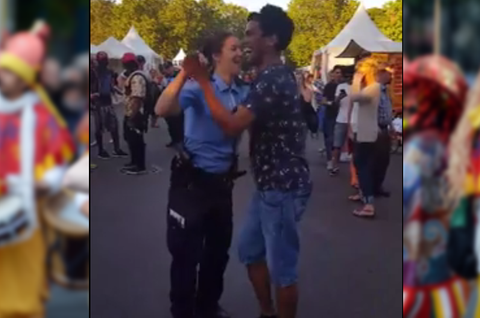 Eine Polizistin tanzt mit einem Besucher beim Karneval der Kulturen in Berlin zu Sambarythmen