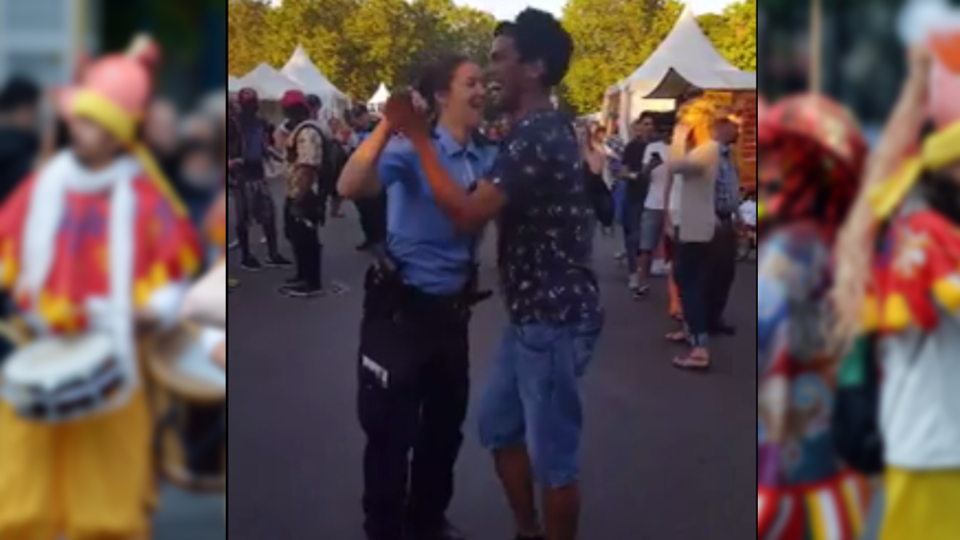 Eine Polizistin tanzt mit einem Besucher beim Karneval der Kulturen in Berlin zu Sambarythmen