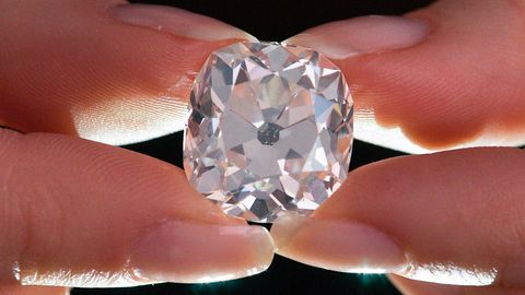 Ein Mitarbeiter des Auktionshauses Sotheby's hält zwischen Daumen und Zeigefingern einen Diamantring