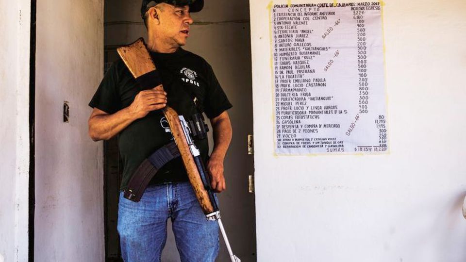 Mexiko: Comandante Carlos Pájaro vor seiner Wache. Neben ihm hängt das Budget der Truppe, für alle einsehbar Comandante Carlos Pájaro vor seiner Wache. Neben ihm hängt das Budget der Truppe, für alle einsehbar