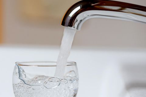 Trinkwasser fließt aus einem Wasserhahn in ein Glas