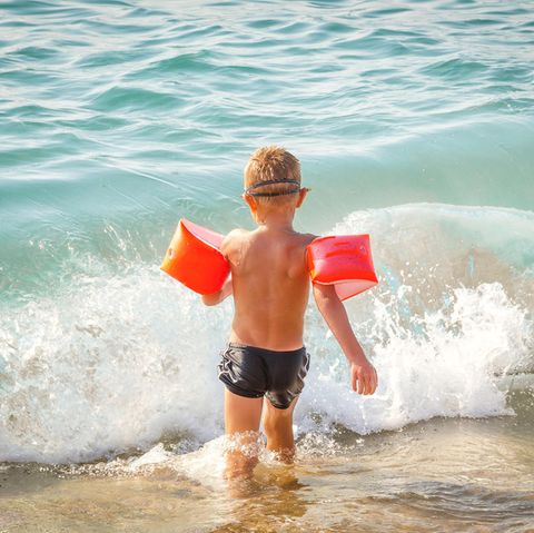 Ein Kind spielt mit Schwimmflügeln am Strand