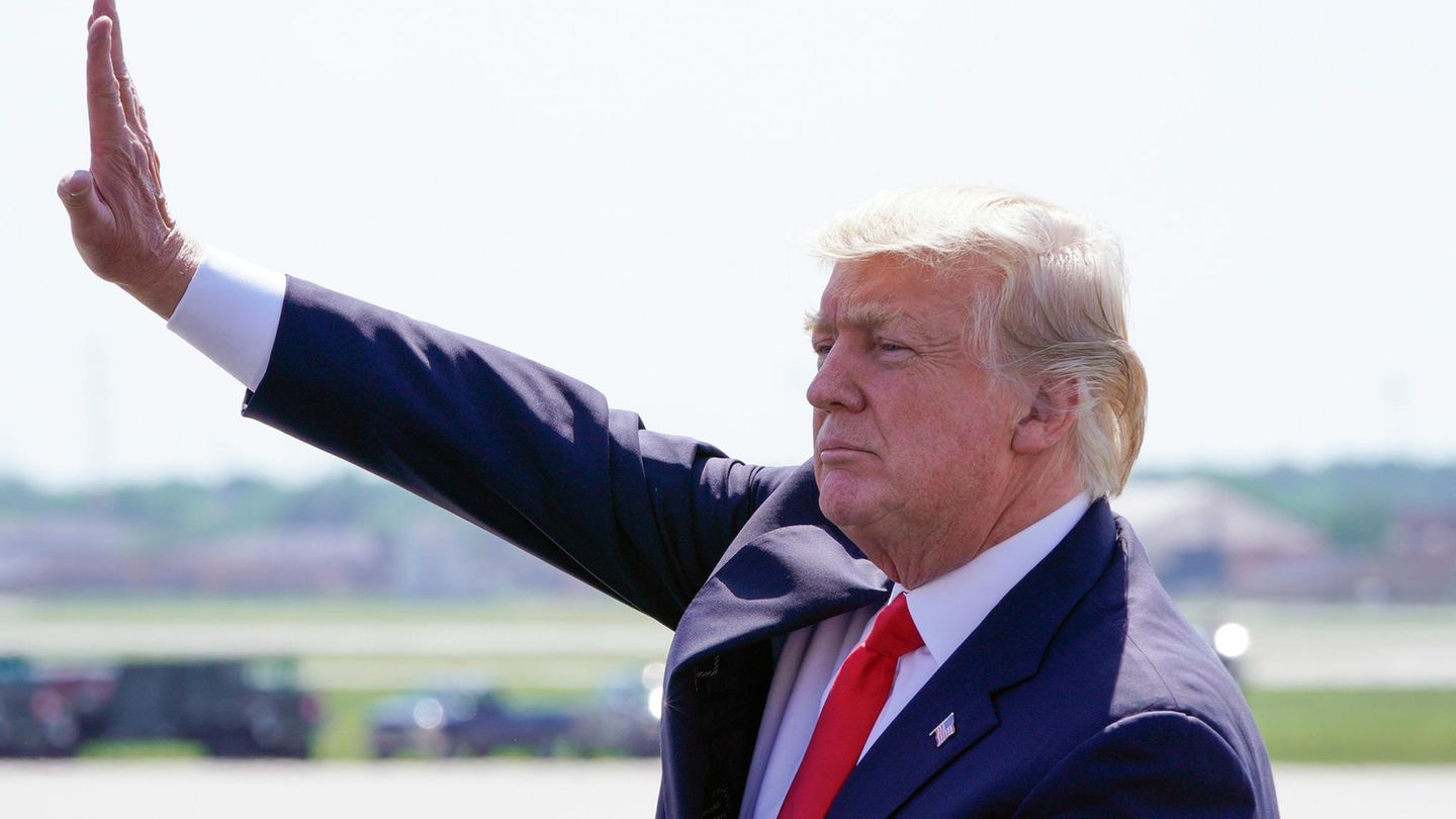Donald Trump grüßt in die Ferne über eine Autodach hinweg