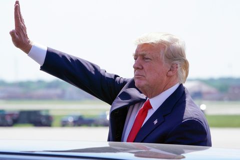 Donald Trump grüßt in die Ferne über eine Autodach hinweg