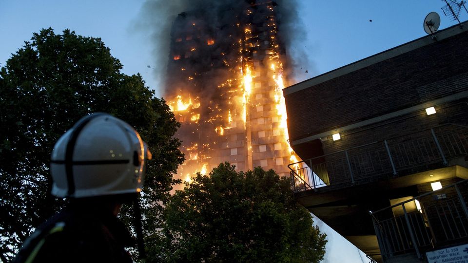 Ein Feuerwehrmann blickt auf den lichterloh brennenden Grenfell Tower in London