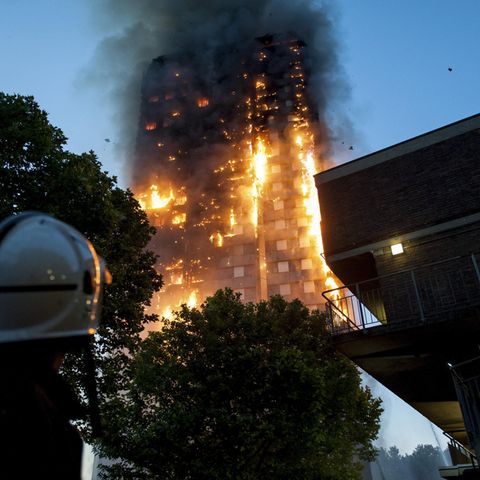 Ein Feuerwehrmann blickt auf den lichterloh brennenden Grenfell Tower in London