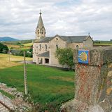Der gelbe Pfeil und Wegsteine mit der Jakobsmuschel sind die meist zuverlässigen Begleiter. Im Bild die Kirche oberhalb der Herberge von Piñera.