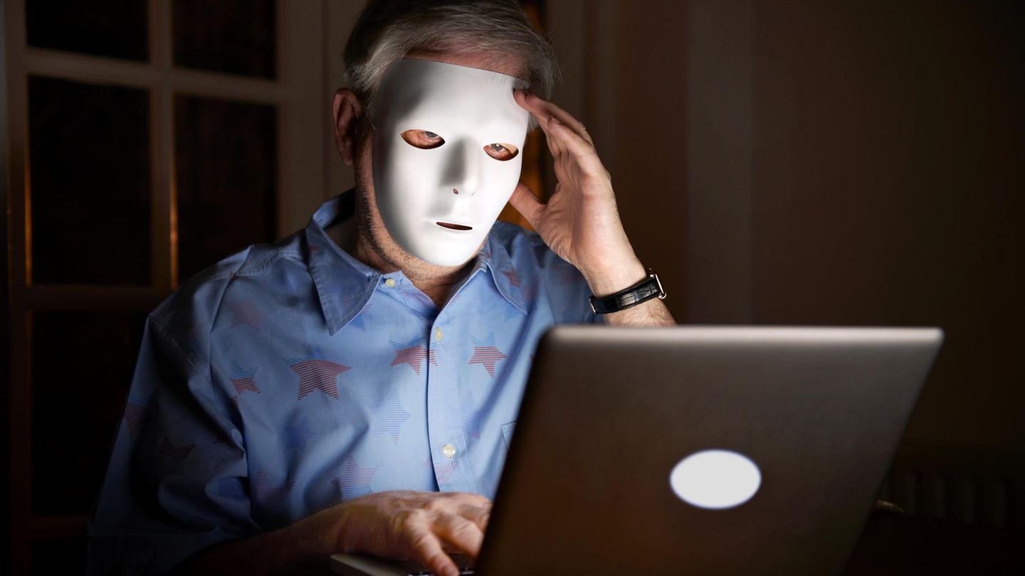 Ein Mann mit einer Maske sucht im Internet ein Nacktbild