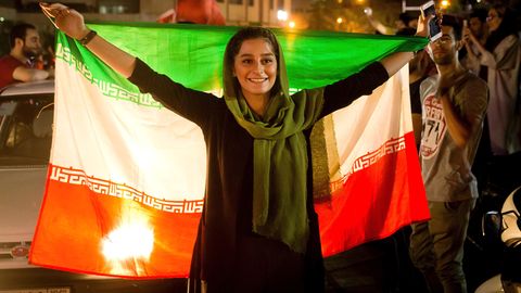 Ein iranische Frau feiert mit der Nationalflagge die Qualifikation des Herren-Fußballteams zur WM 2018 in Russland